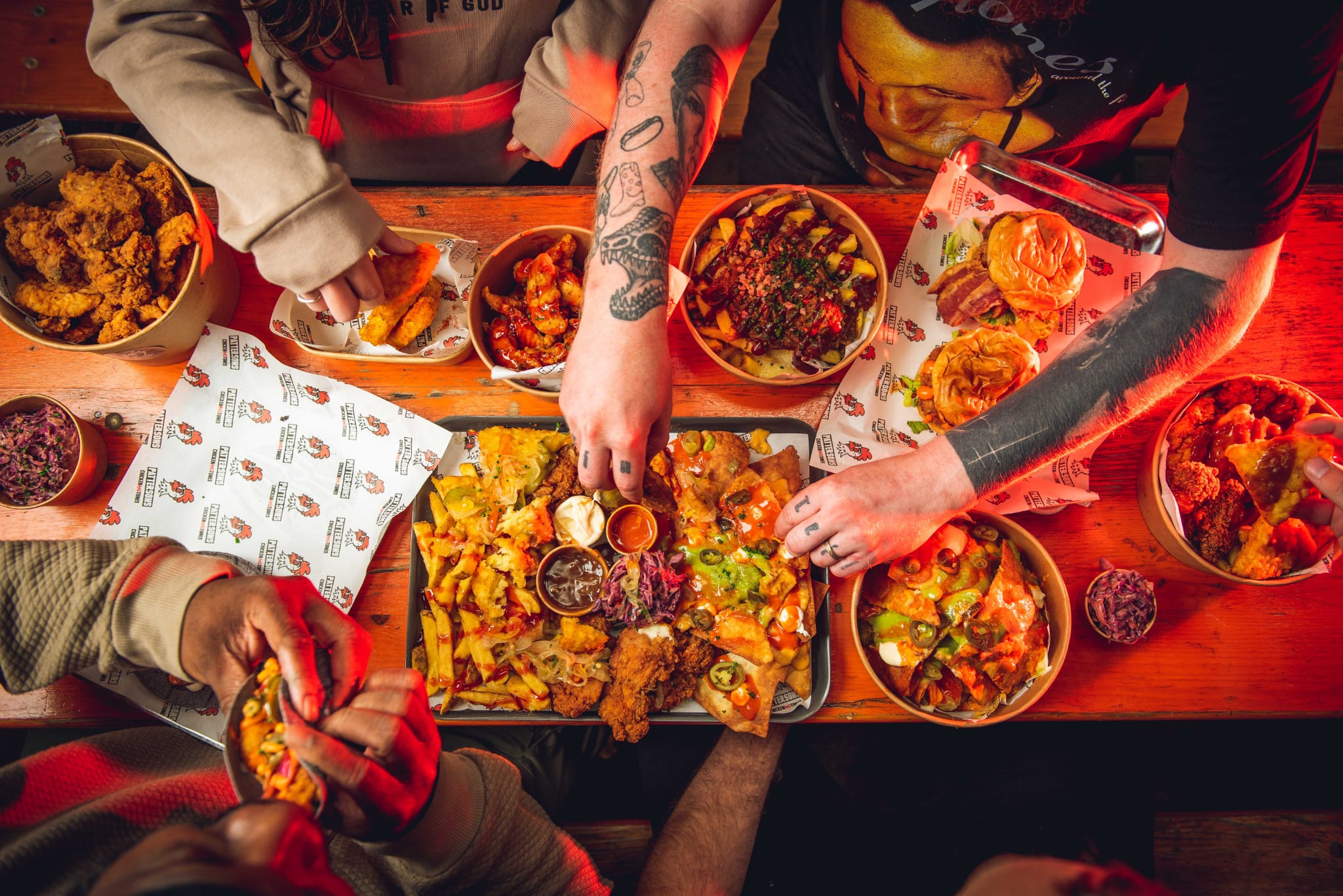 Friends sharing Pattersons chicken, burgers and loaded fries around a table