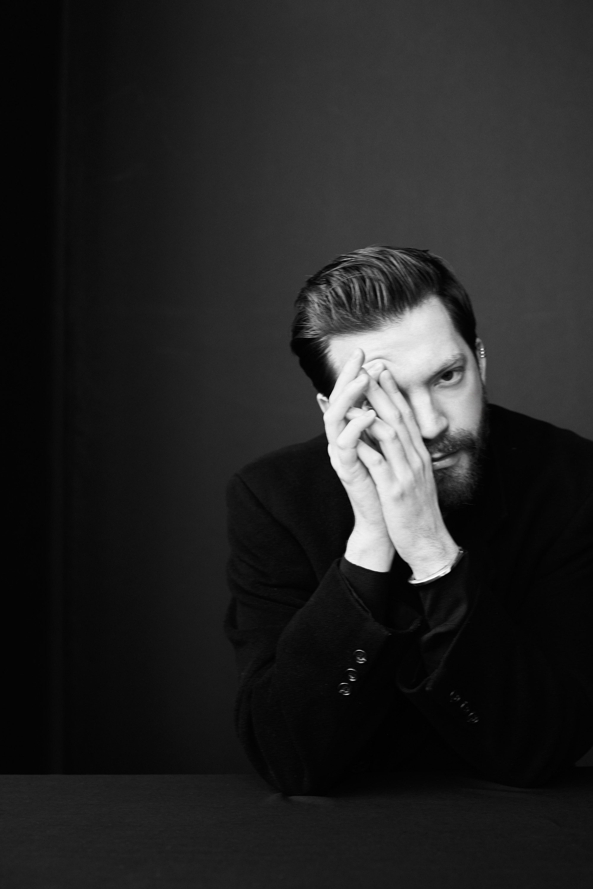 Black and white portrait of Bailey Moon resting his face on folded hands at a table.