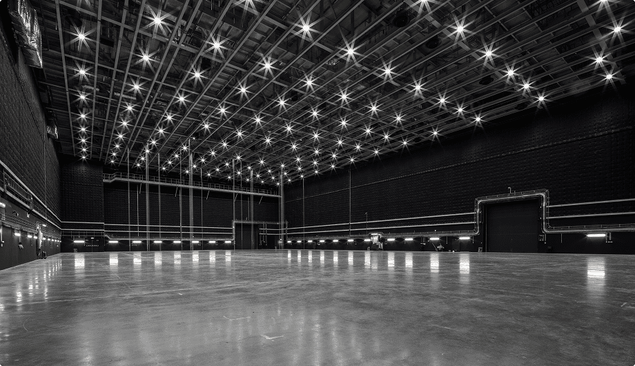 Large empty industrial studio with polished floor and bright ceiling lights in a grid pattern.