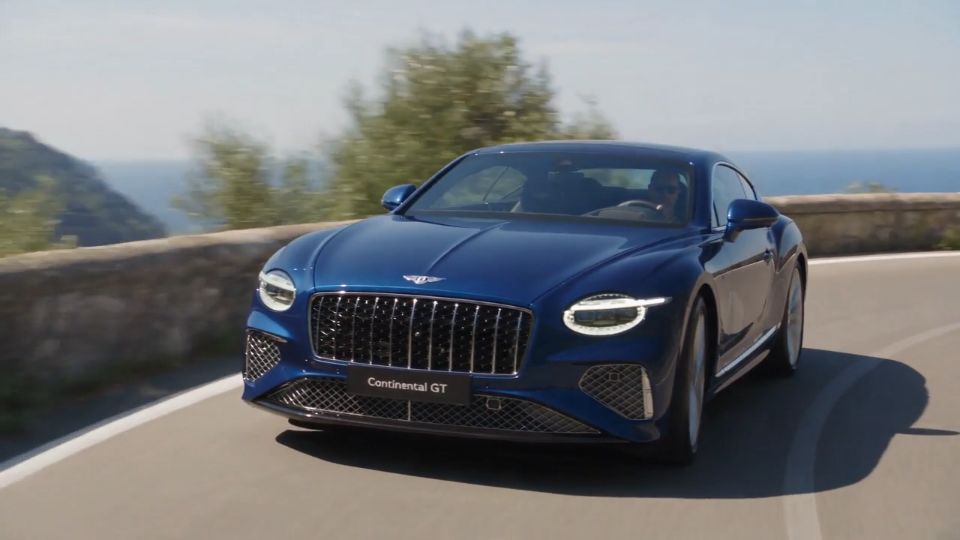 Blue Bentley Continental GT on a Mediterranean coastal road