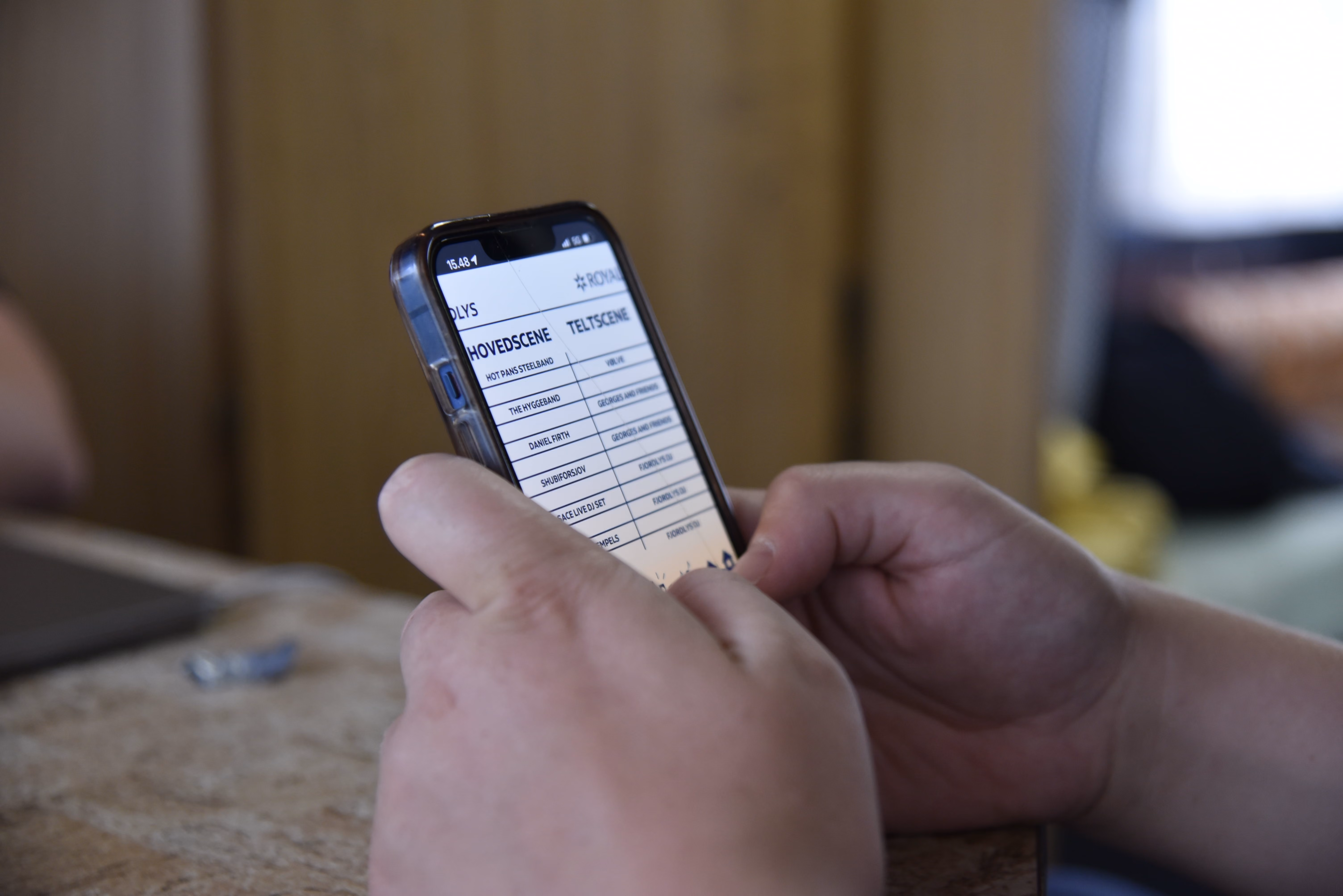 Hænder holder en mobiltelefon, der har en spilleplan åben for programmet på Fjordlys Festival 2024
