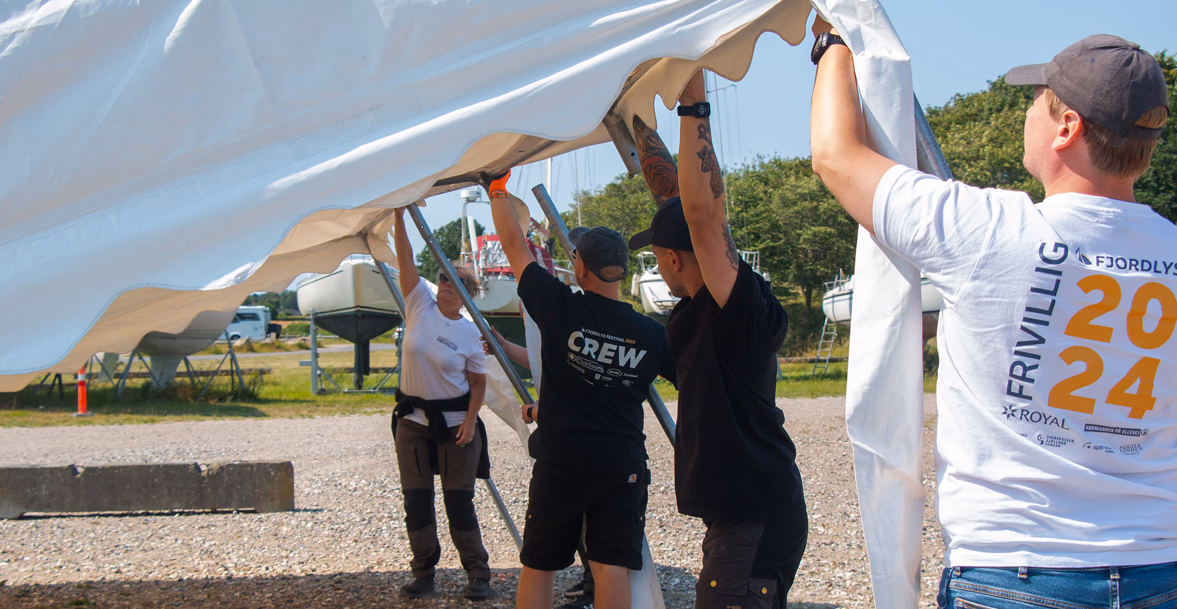 Frivillige arbejder på at sætte et telt op på festivalpladsen