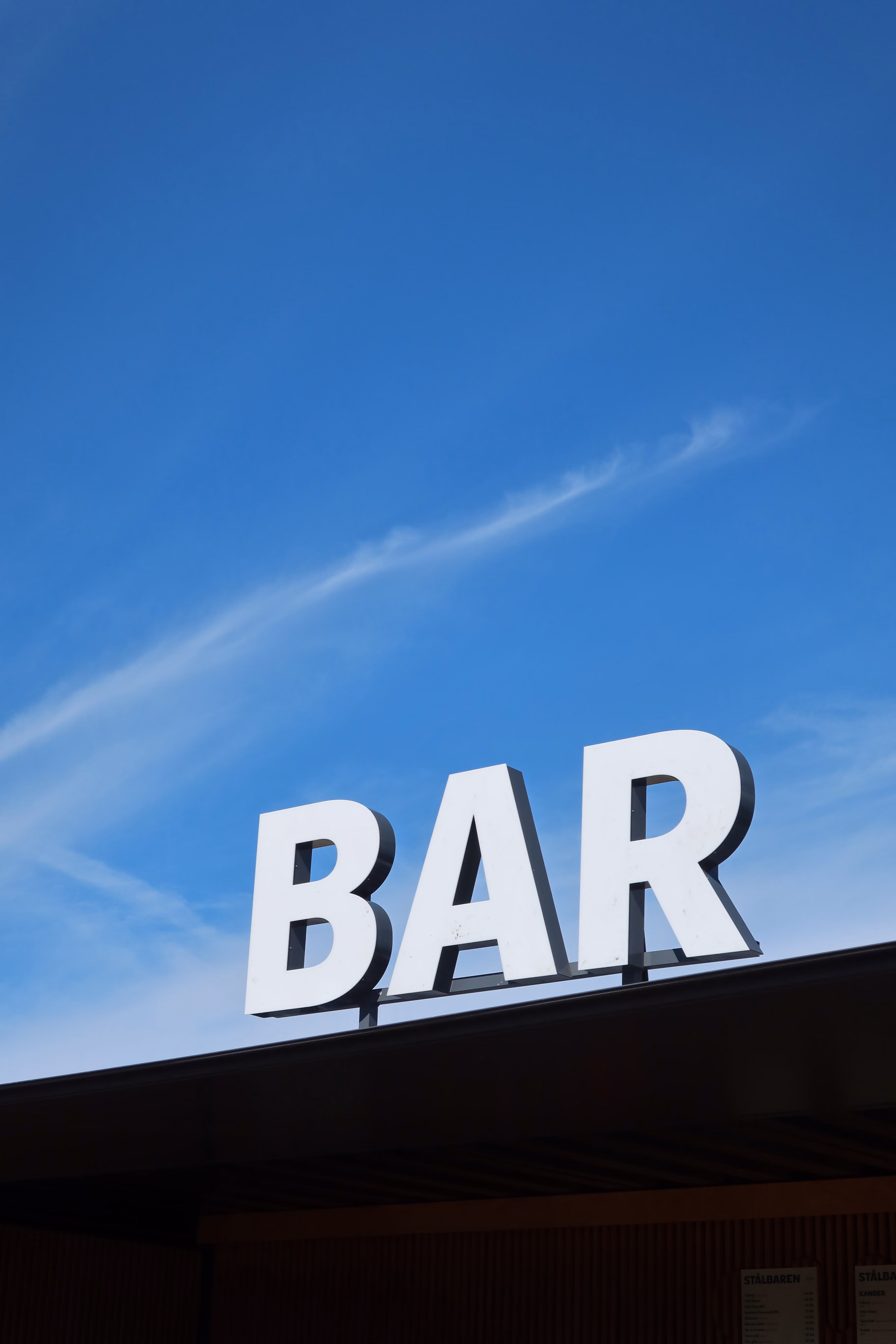 Barskiltet fra en bar på festivalpladsen med en blå himmel i baggrunden