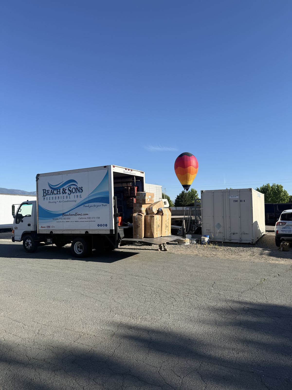 Beach and Sons box truck at a job site with a hot air balloon in the morning sky