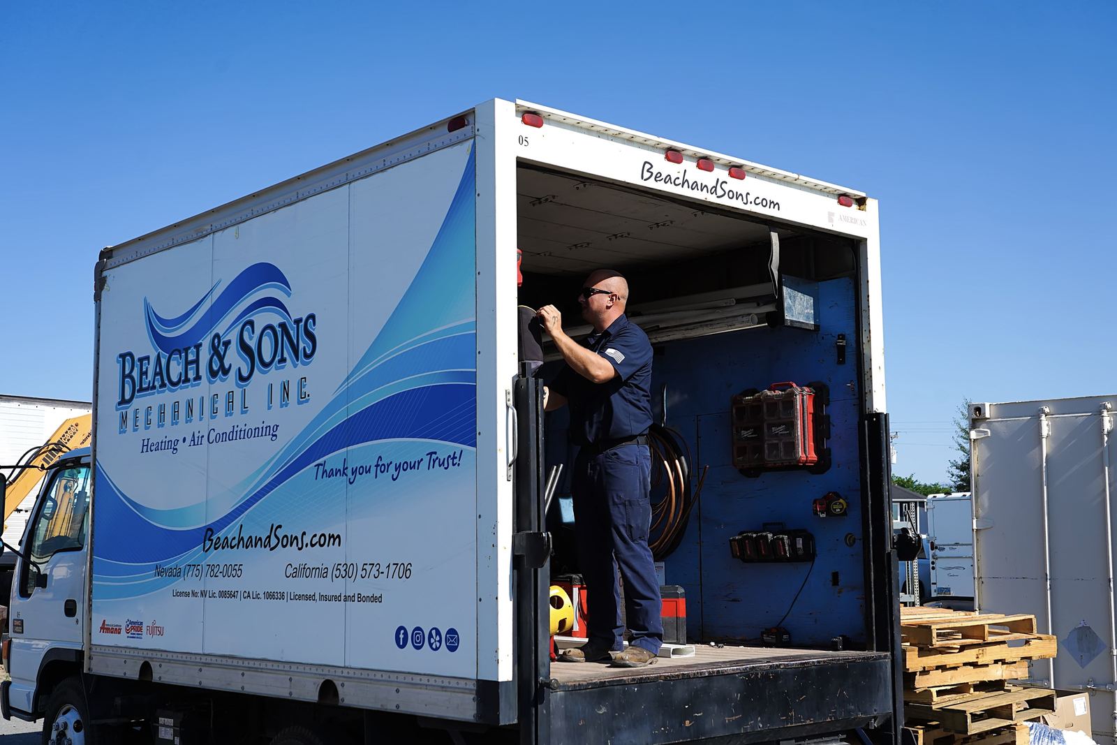Beach and Sons technician loading equipment in a branded box truck