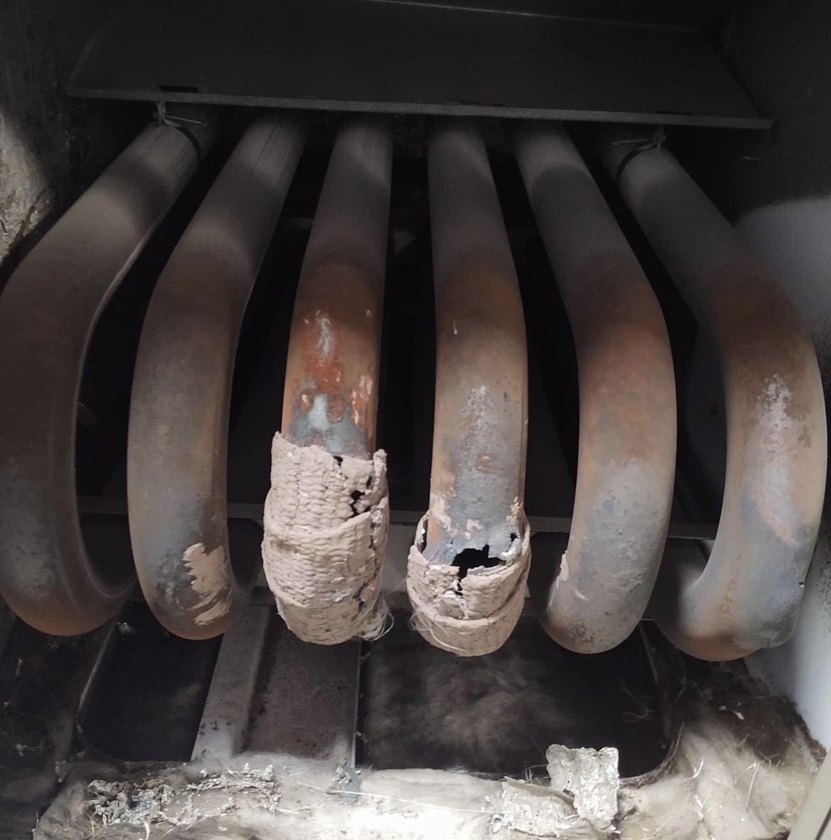 Severely damaged heat exchanger burner tubes inside a furnace