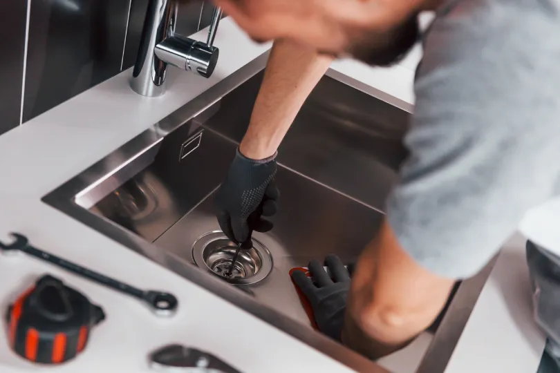 A technician working on a sink's drain