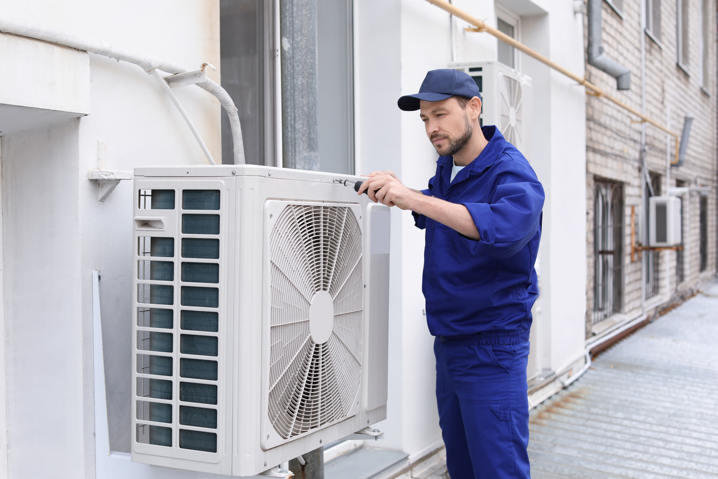 Technician making urgent repairs to an outdoor HVAC unit