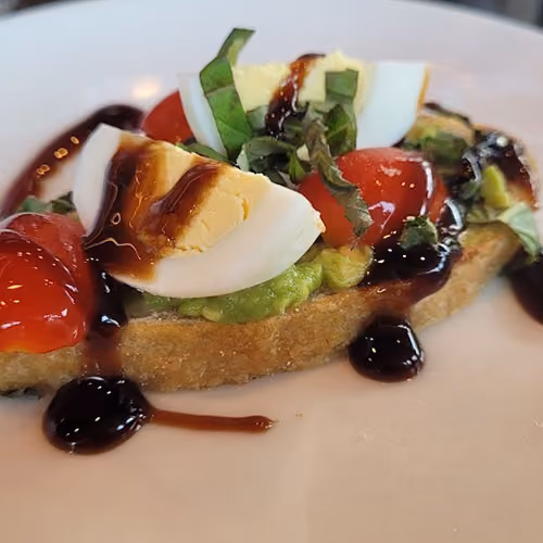 Toast topped with avocado, cherry tomatoes, sliced boiled egg, basil, and balsamic glaze.