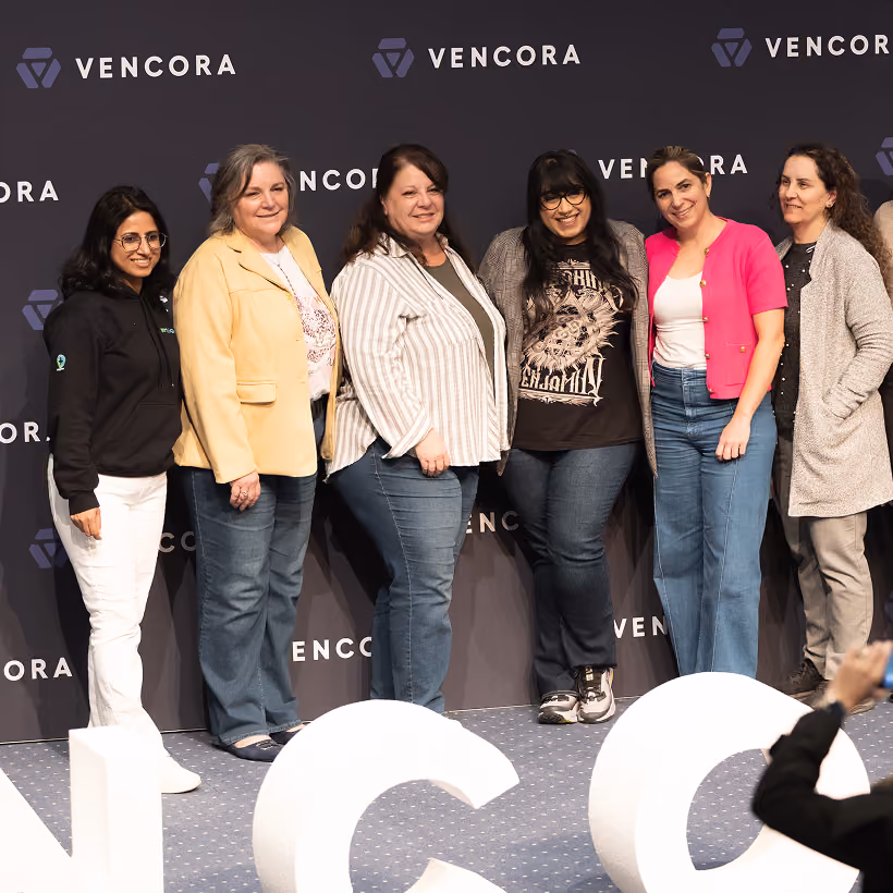 A group of women posing together in front of a Vencora-branded event backdrop