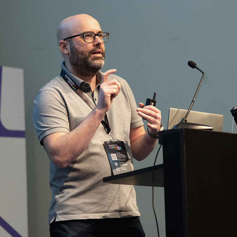 A speaker presenting at a podium with a microphone
