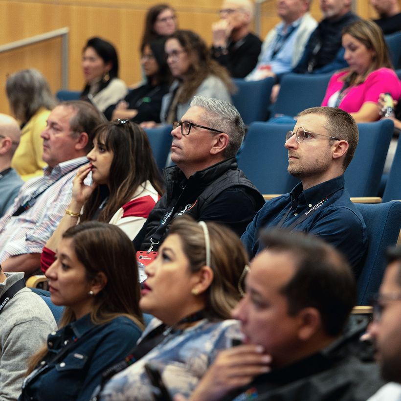 Attendees seated in rows listening to a presentation in an auditorium