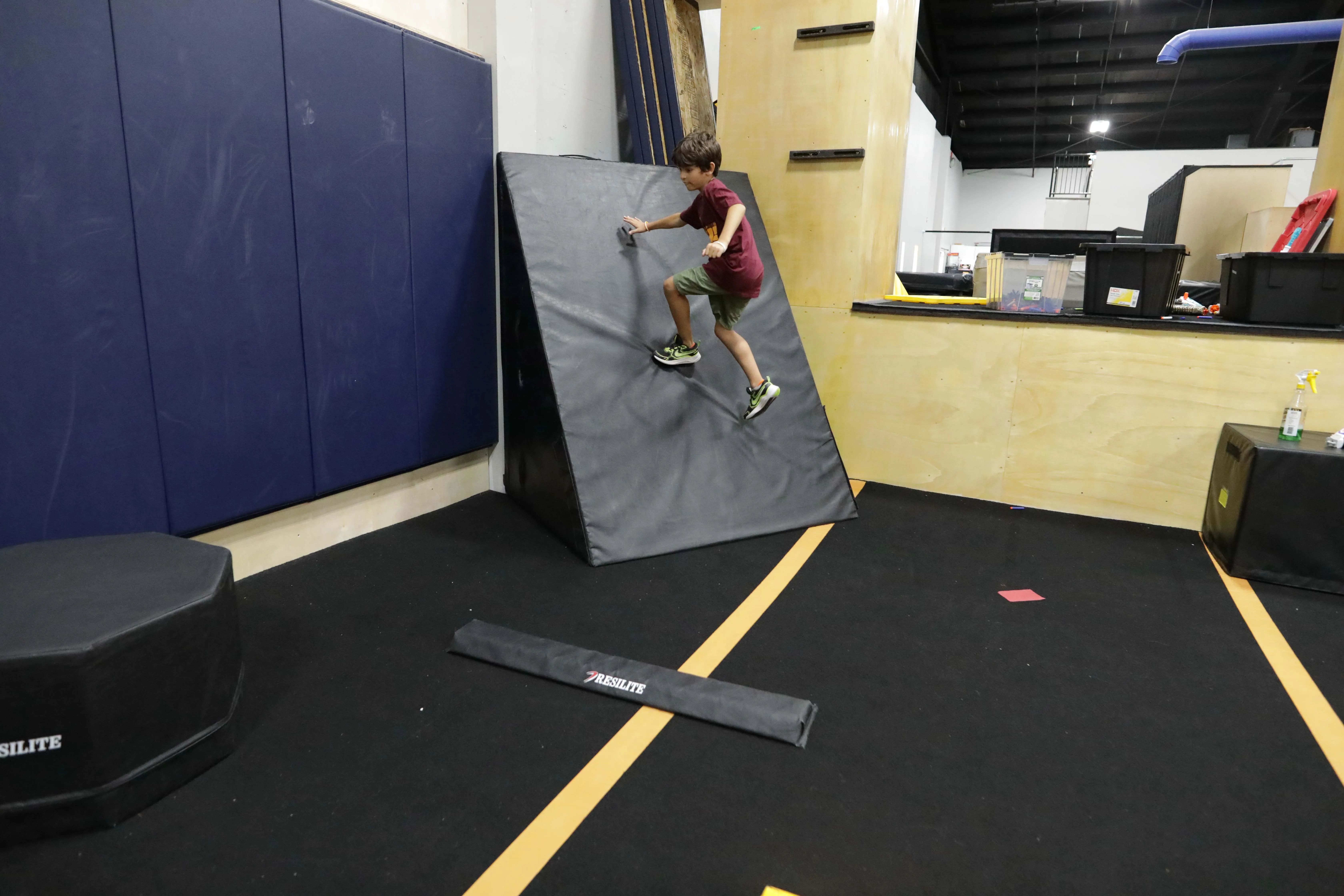 A young athlete training on wooden parkour obstacles at HUB Parkour