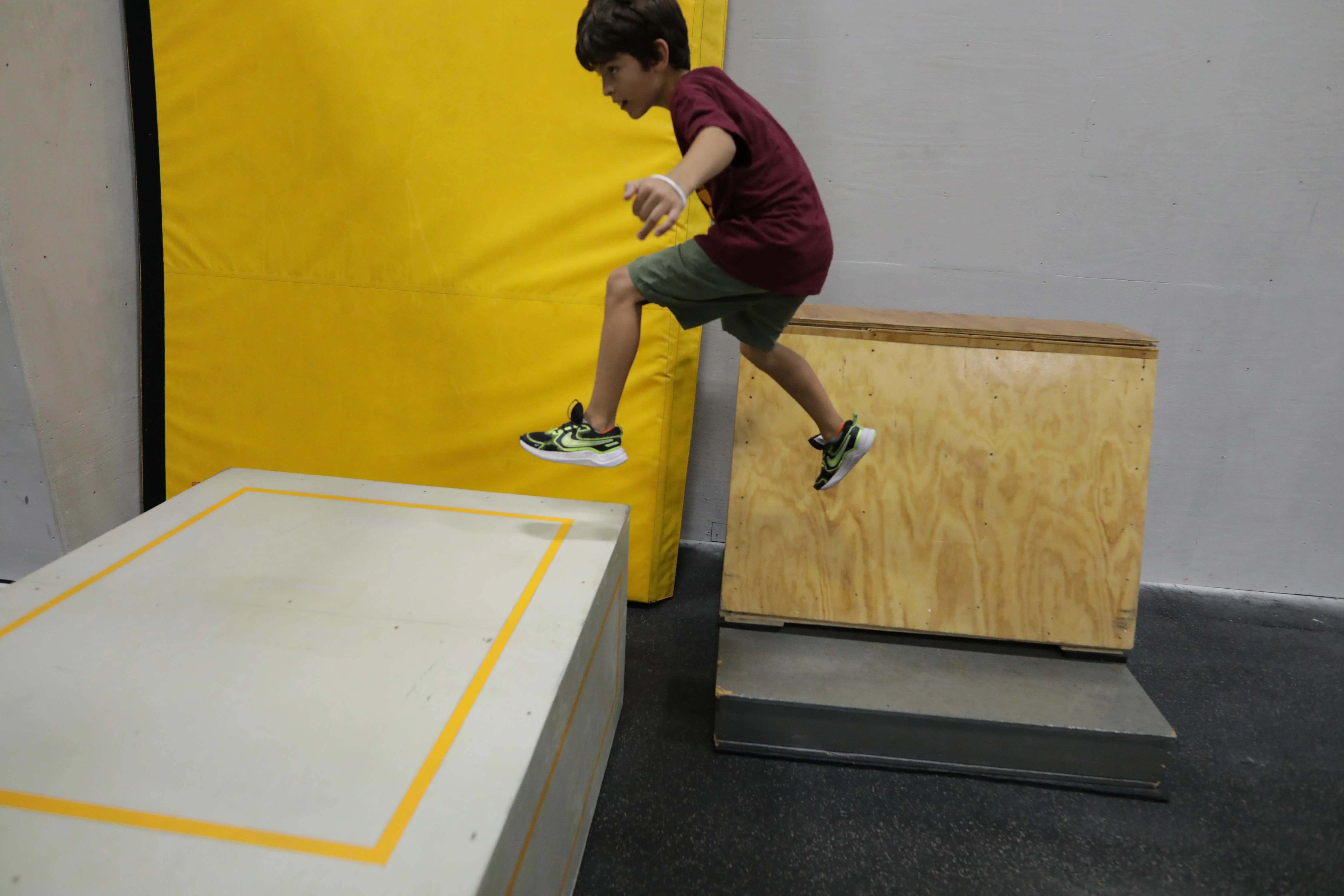 An adult athlete training parkour on wooden obstacles at HUB Parkour