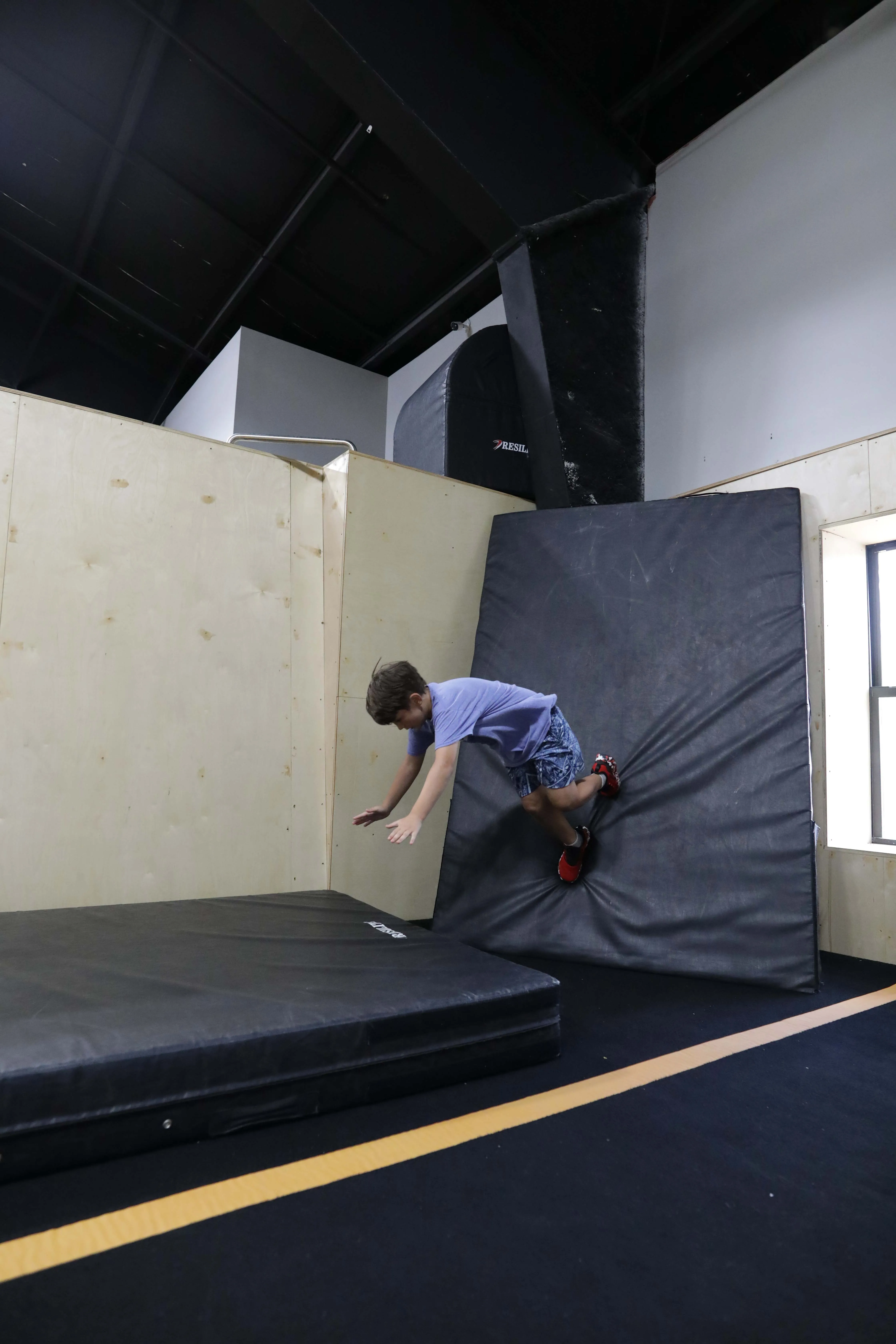 A child climbing and balancing on a wooden obstacle during parkour training