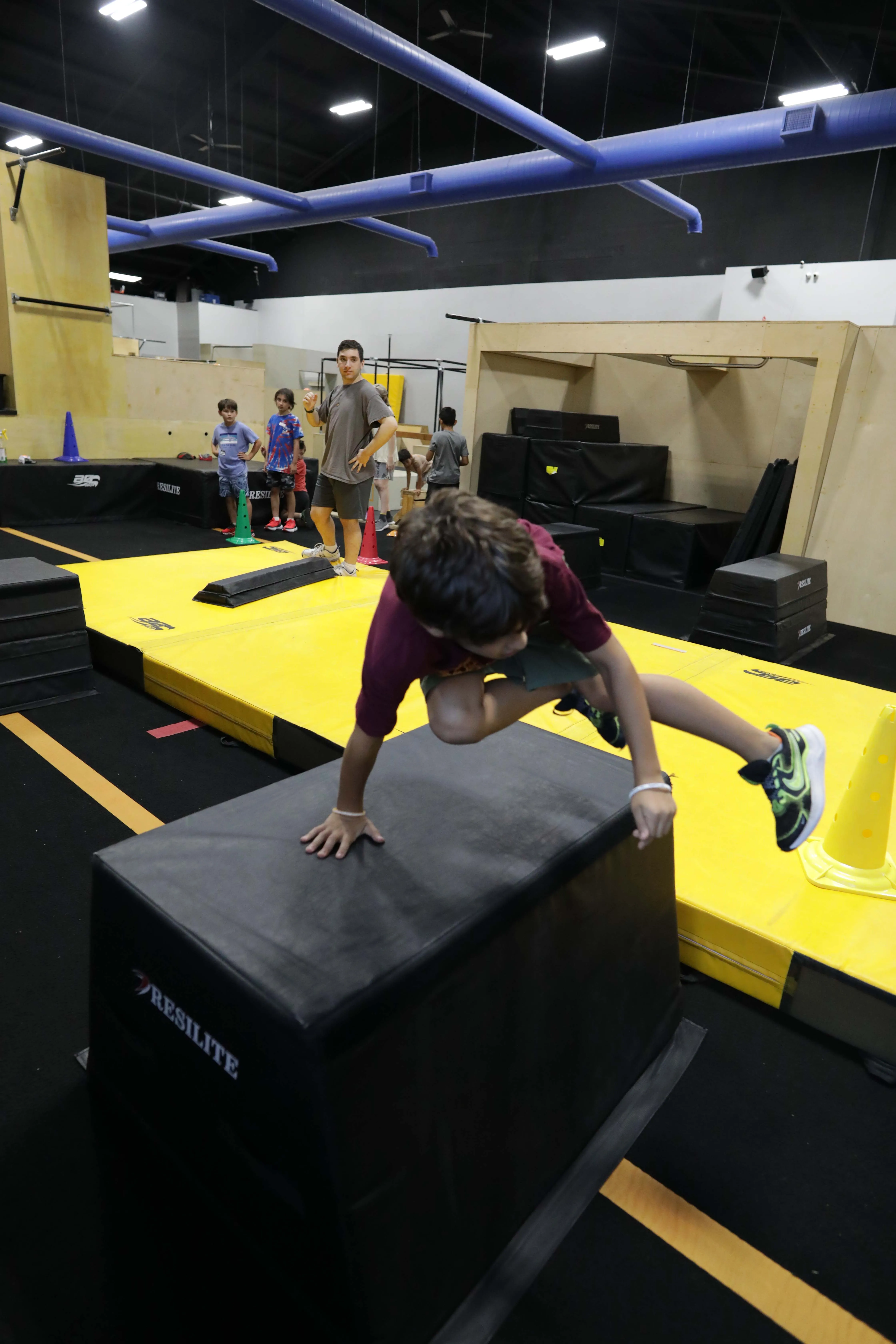 An athlete in mid-movement over a wooden obstacle at HUB Parkour