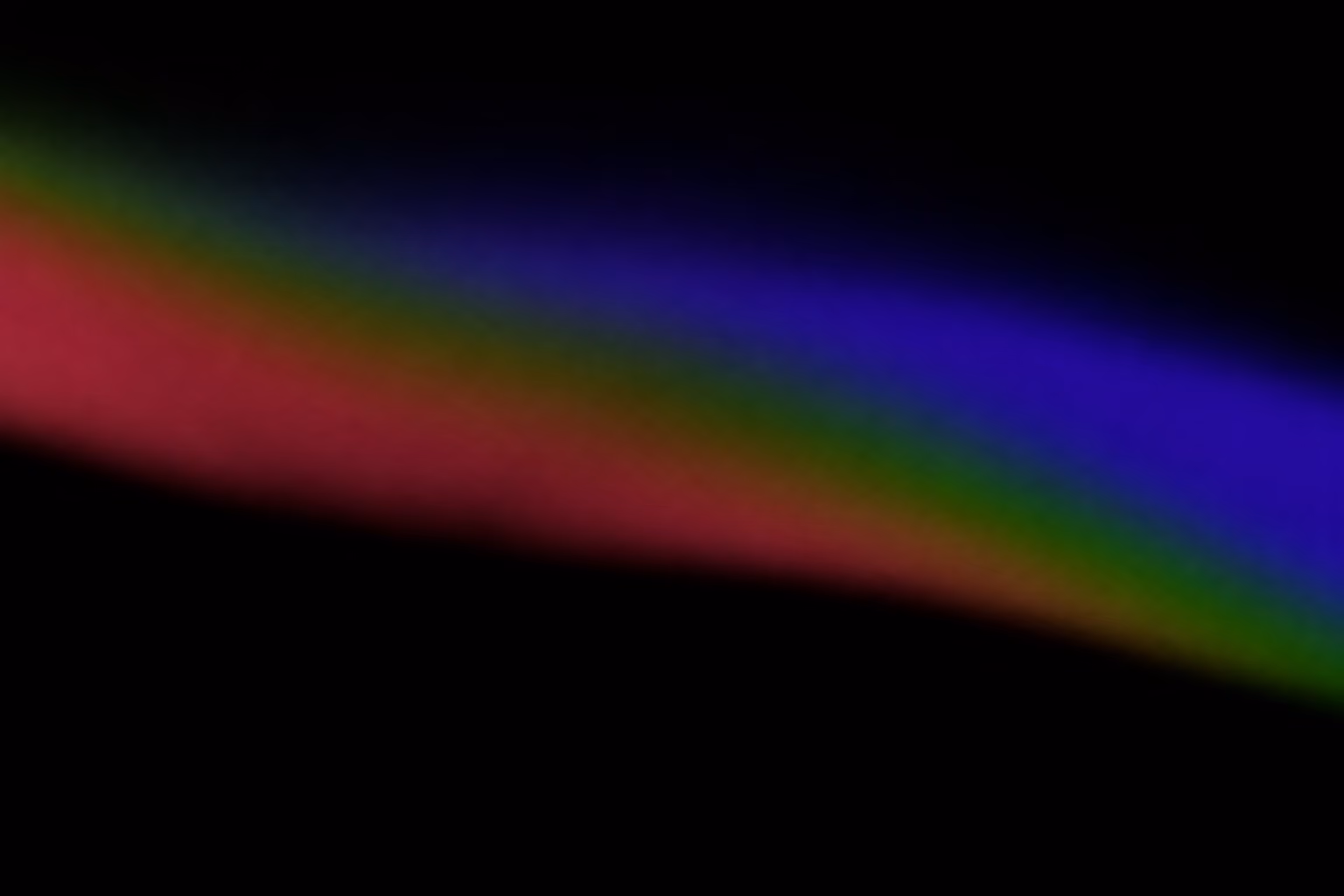 Blurred diagonal gradient bands of blue, green, and red on a black background.