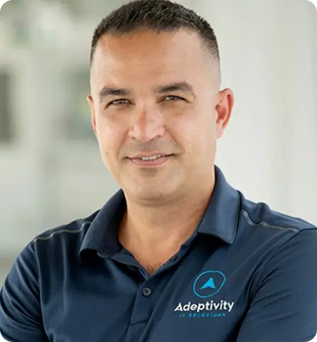 Man wearing navy polo shirt with Adeptivity IT Solutions logo smiling at the camera.