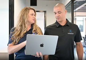 Woman and man reviewing a laptop together in a modern office space.