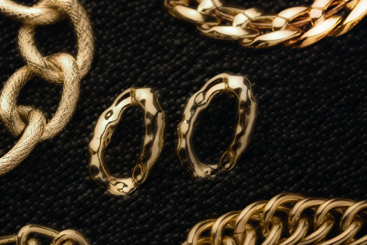 Handmade gold hoop earrings beside gold chains