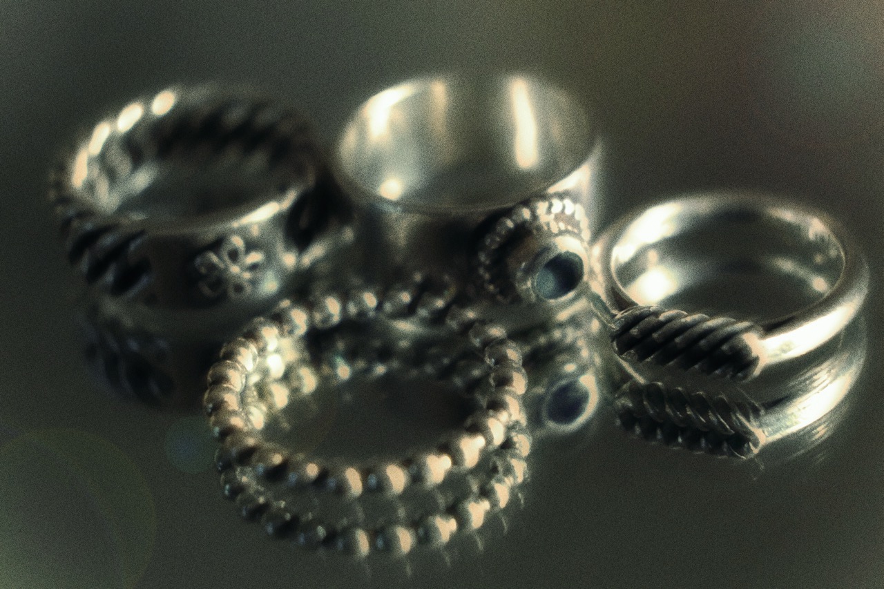 Patterned sterling silver rings on a reflective surface