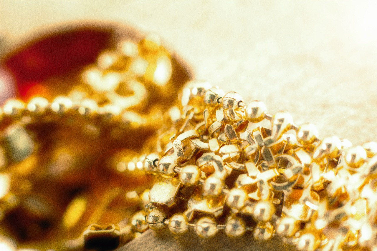 Fine gold chain necklaces piled in warm light