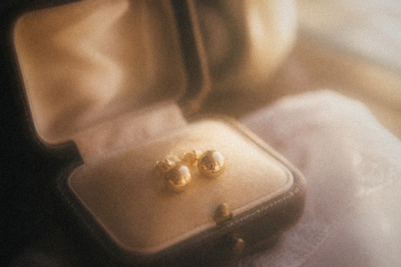 Finished gold hoop earrings resting on dark fabric