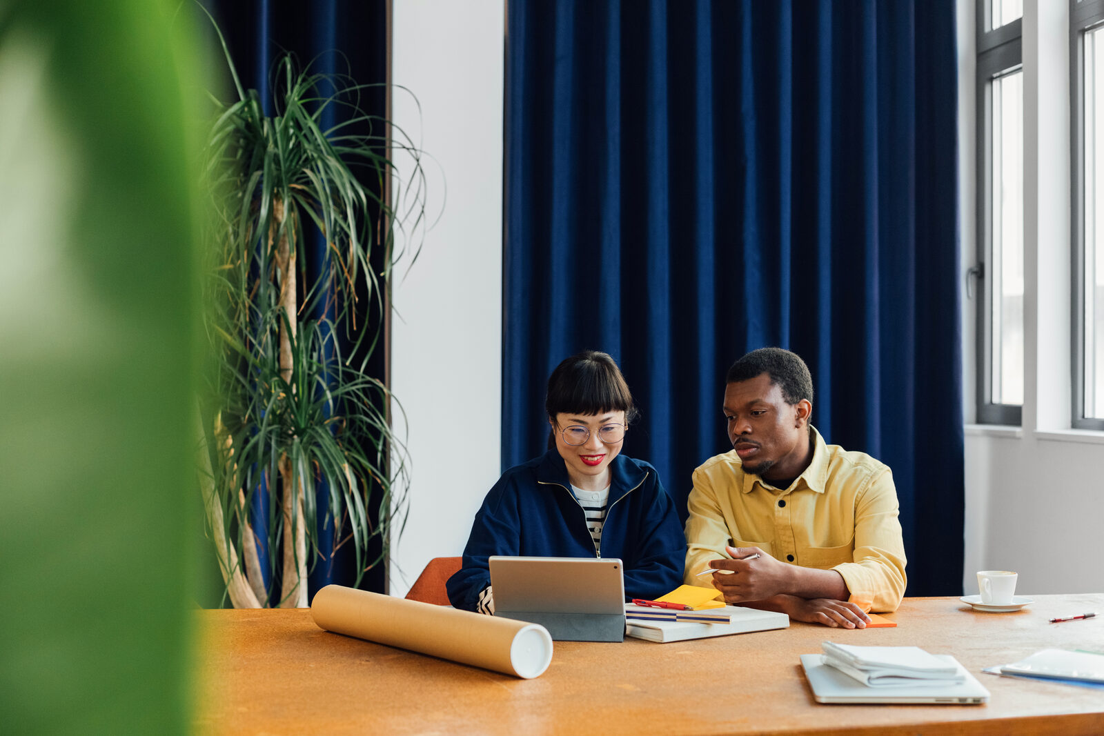 Two colleagues talking across a desk in a bright workspace