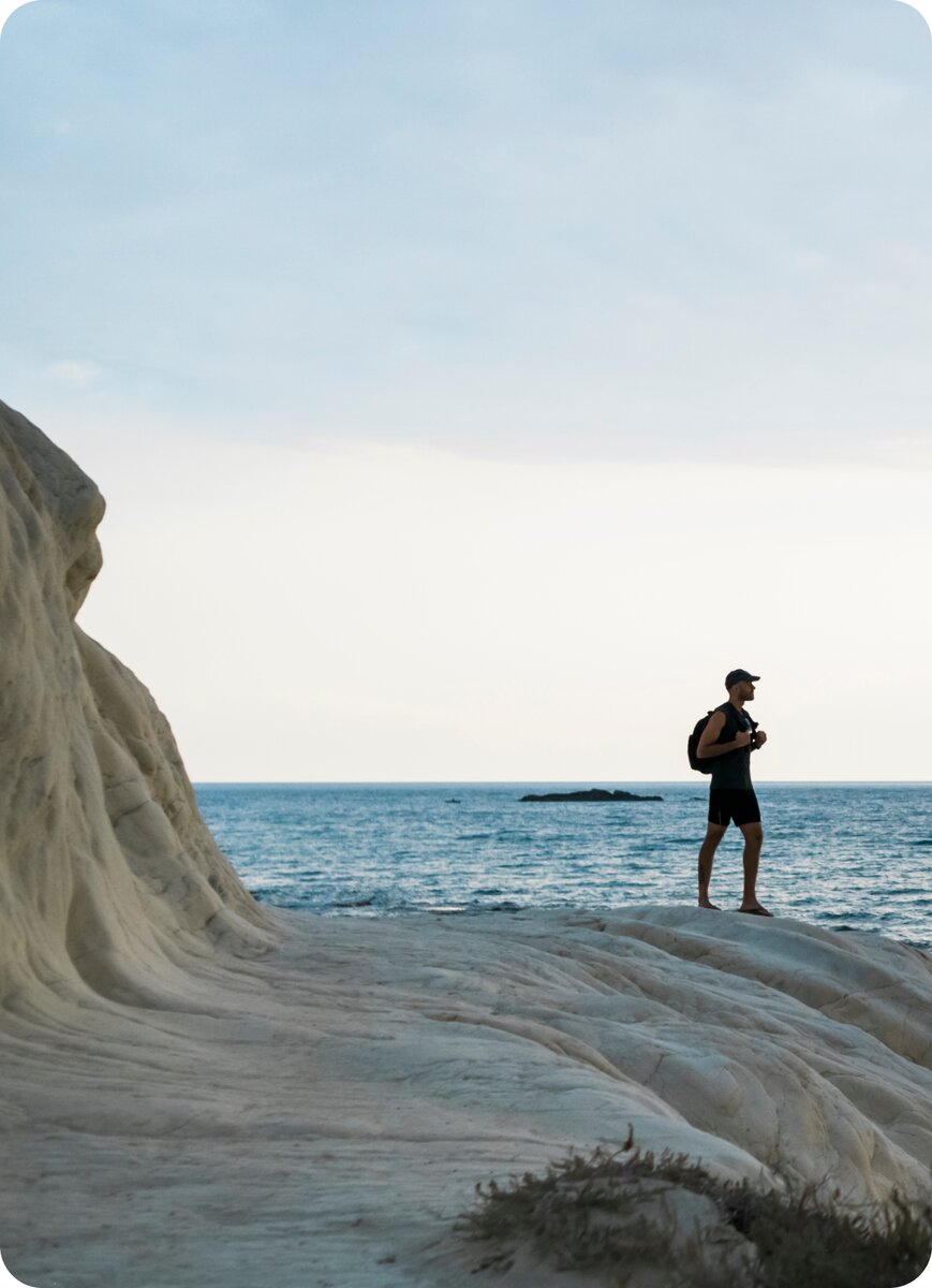 A person standing alone on coastal rocks looking out to sea