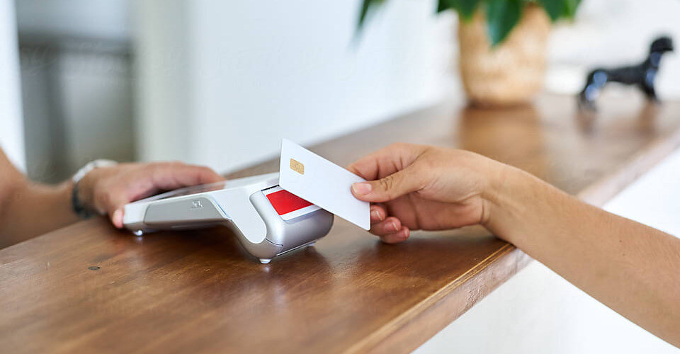 A patient tapping a payment card on a card reader at a reception desk