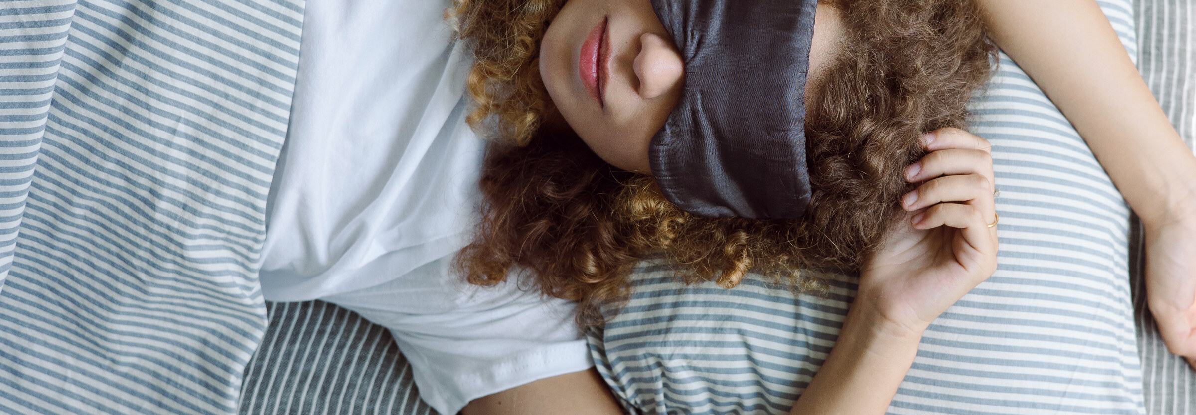 A person asleep in bed wearing an eye mask