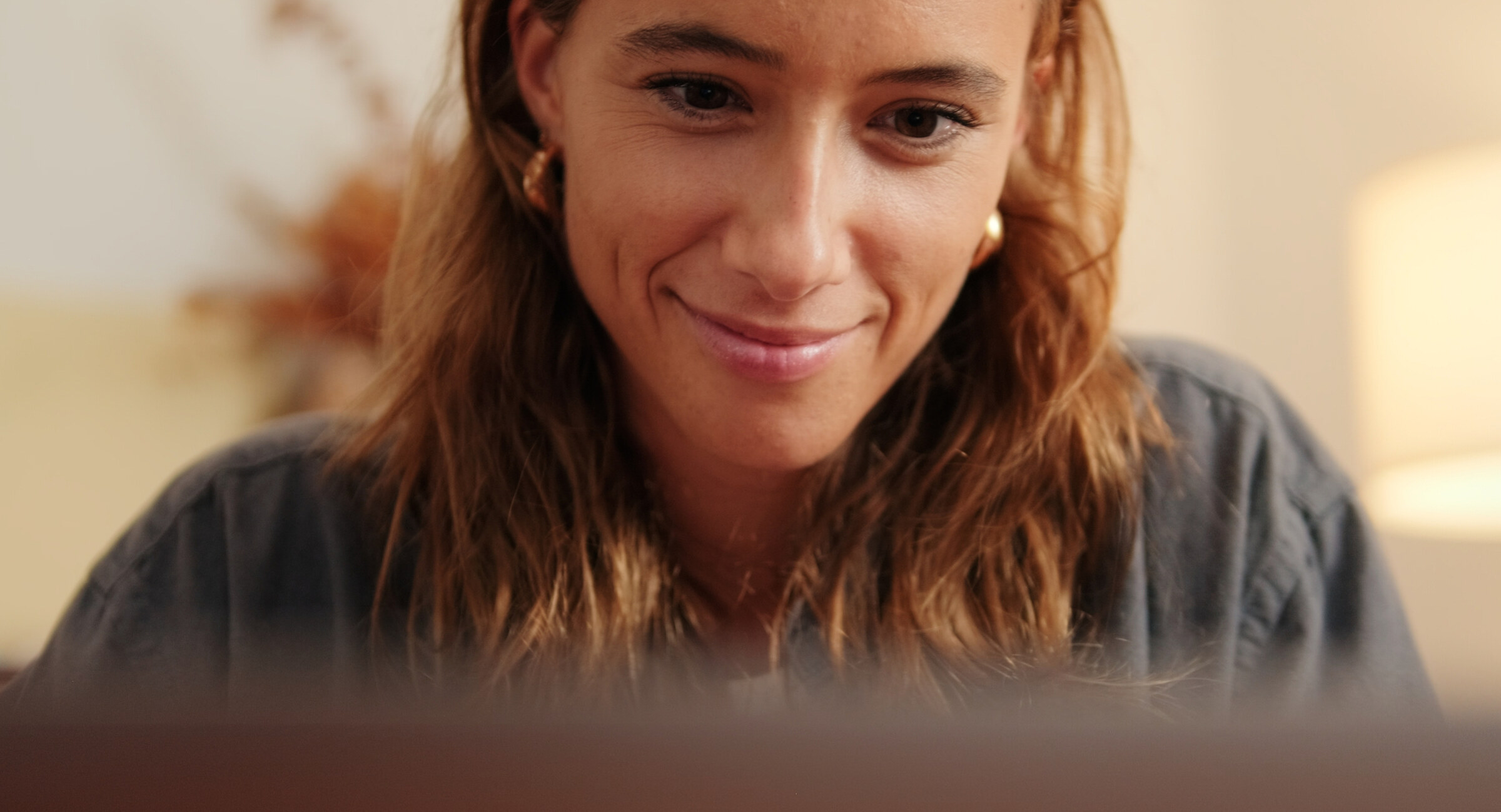 A woman smiling as she reads her laptop screen at home