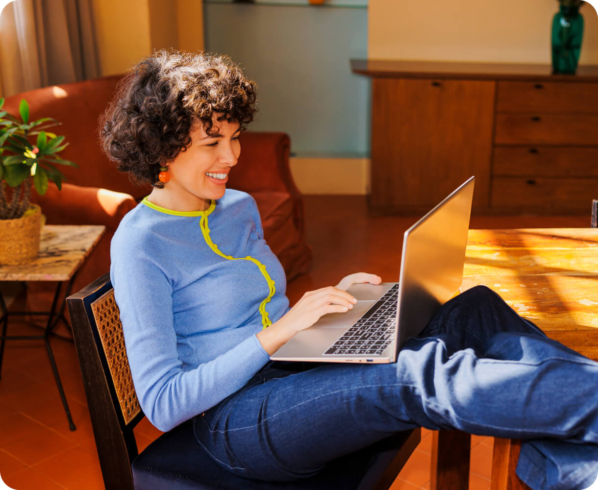 A woman smiling at a laptop in her living room