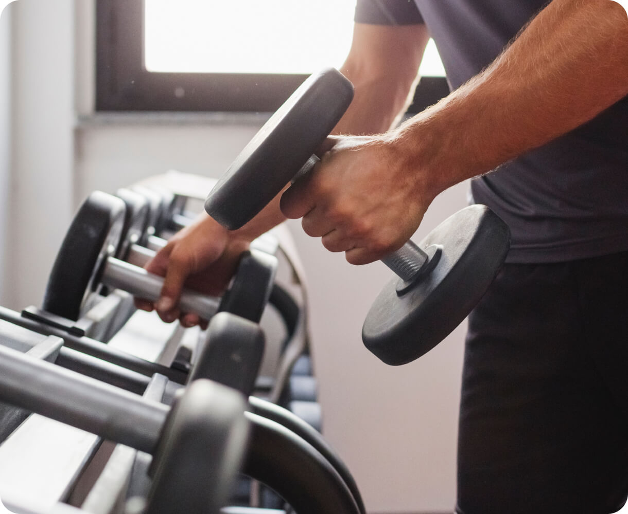 A person lifting a dumbbell from a gym rack