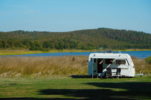A serene lakeside camping scene with a caravan overlooking a picturesque landscape