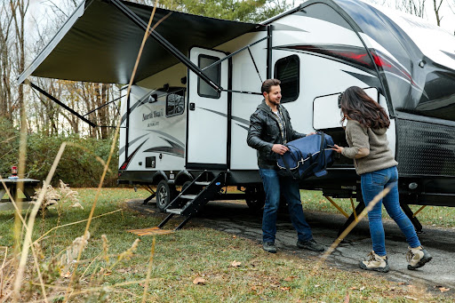 couple unpack caravan at a camp site