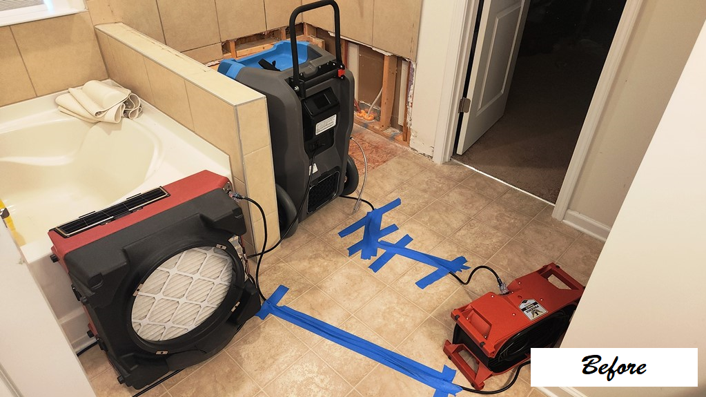 Bathroom with drying equipment and a moisture-mapped floor before restoration