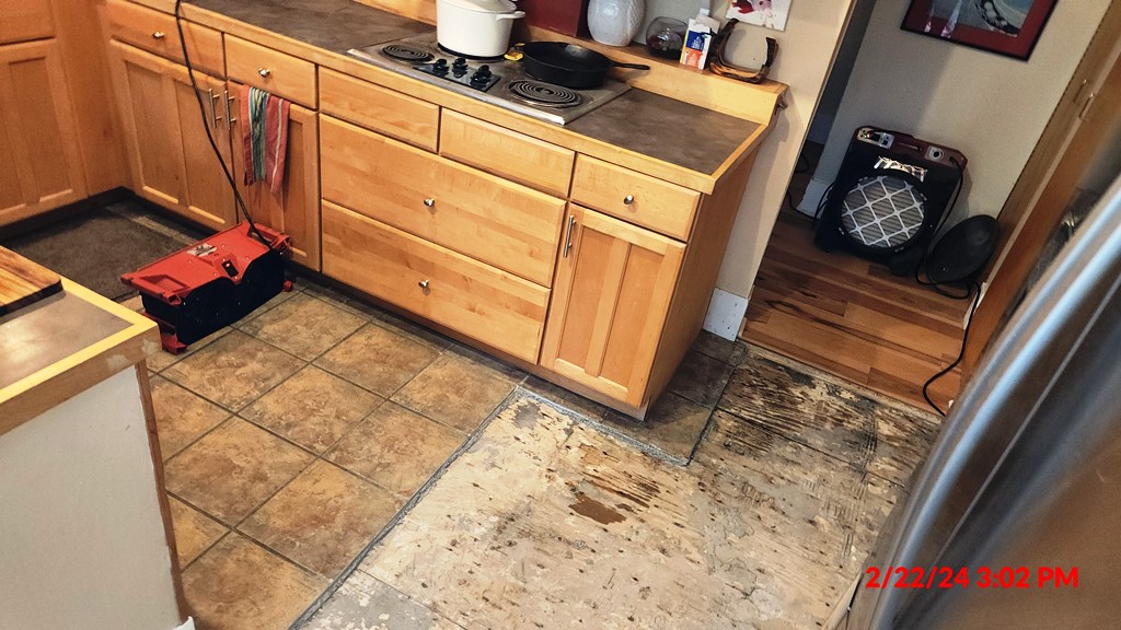 Kitchen with a damaged tile floor and drying equipment after a water leak