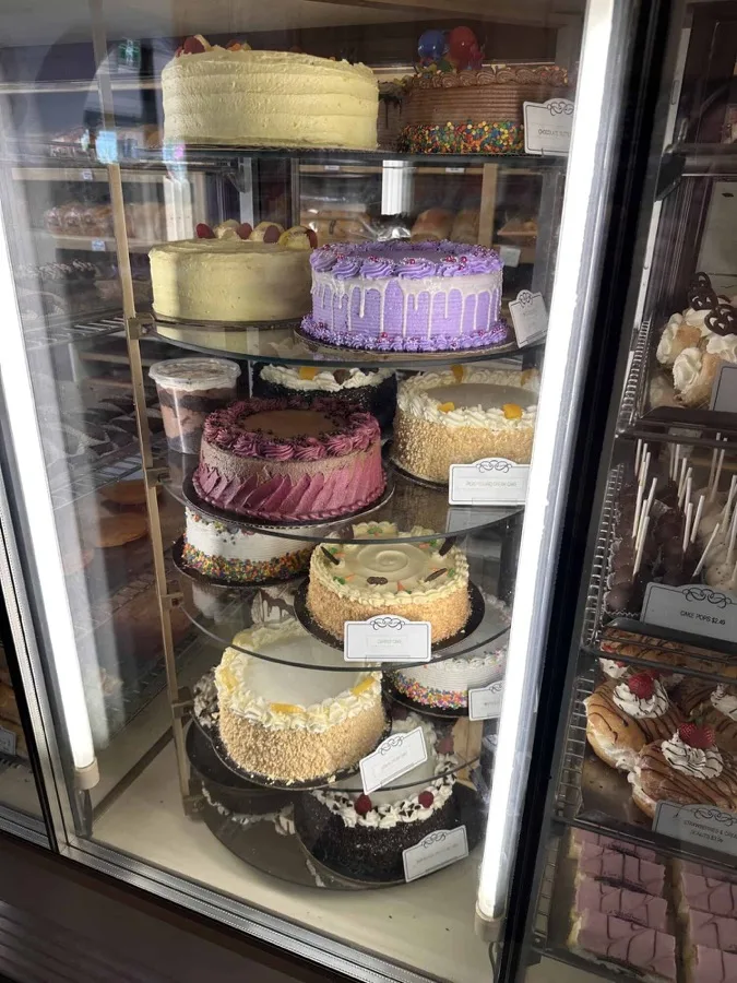 Decorated cakes on tiered shelves in the bakery display case