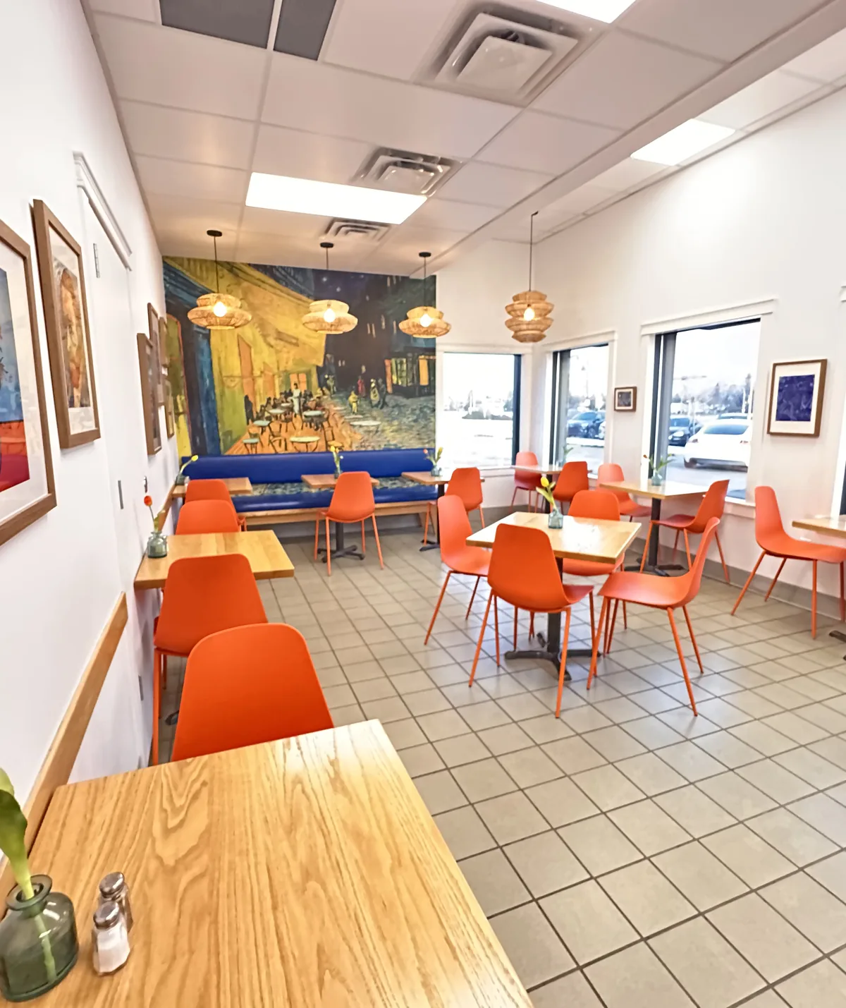 Inside Coaldale Bakery, orange chairs and wooden tables in the seating area beside a painted mural