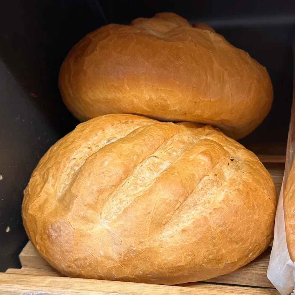 Two golden round Italian loaves on a wooden shelf at Coaldale Bakery