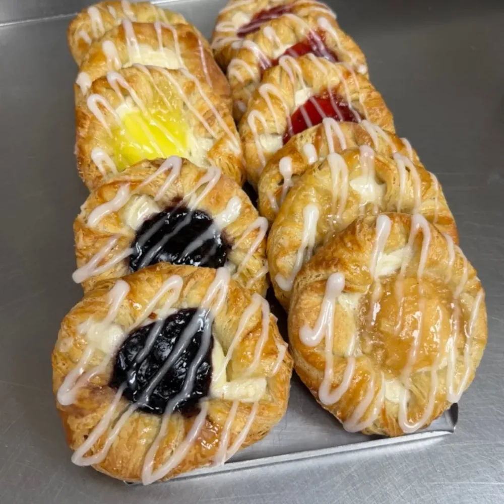 A tray of glazed Danish pastries with fruit and custard fillings