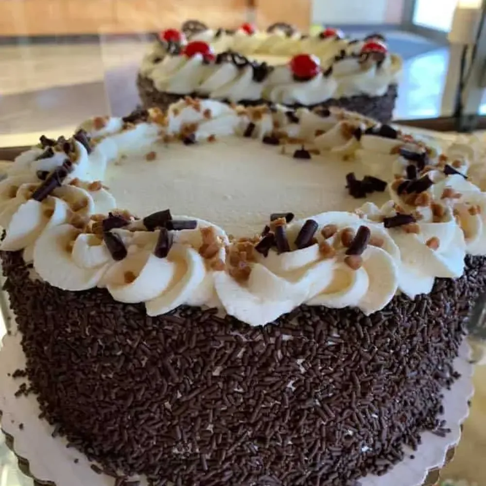 Chocolate-coated cakes topped with piped cream in the bakery display