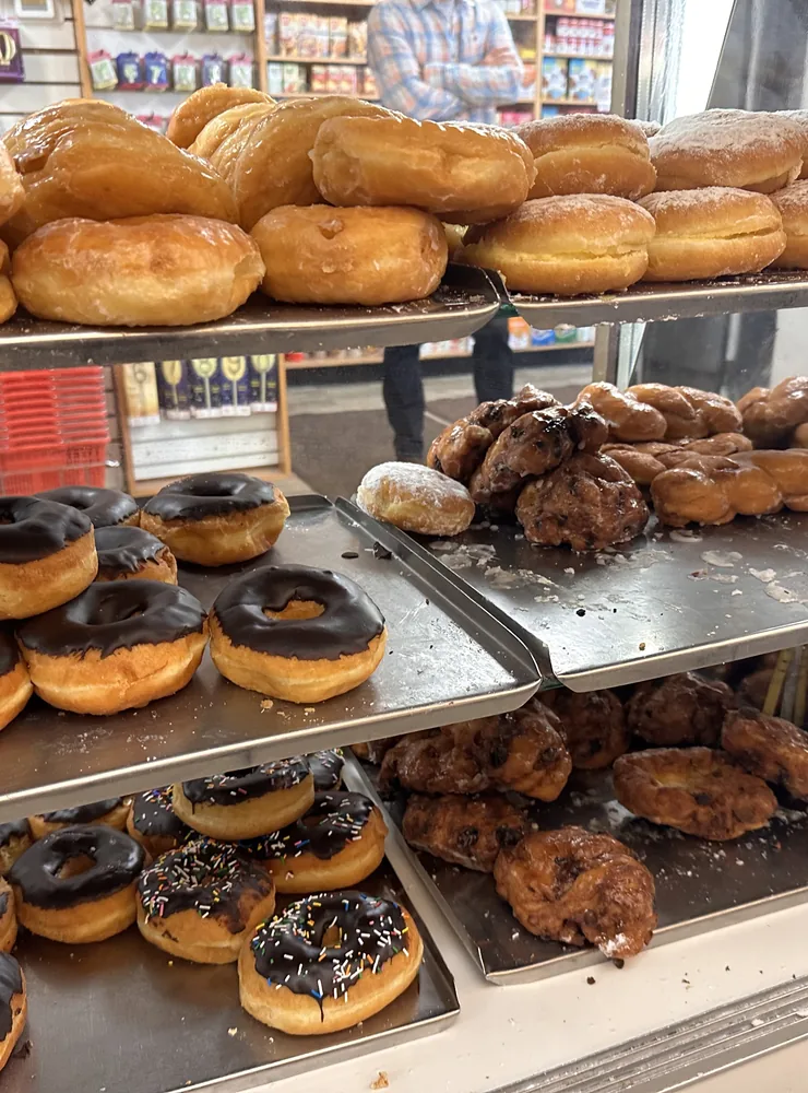 Donuts and long johns arranged on the tiered racks in the display case