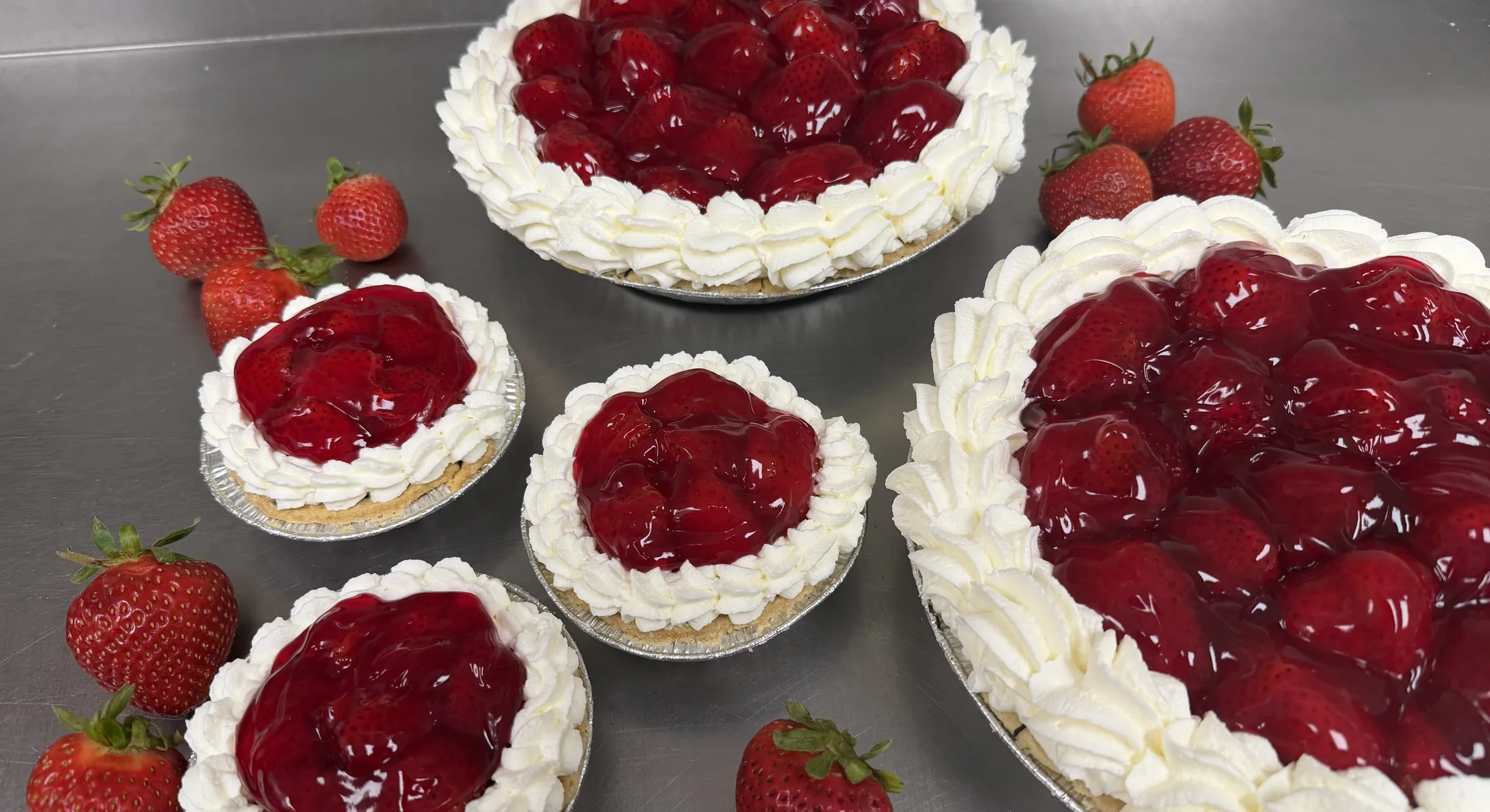 Strawberry cream pies and tarts topped with glazed strawberries