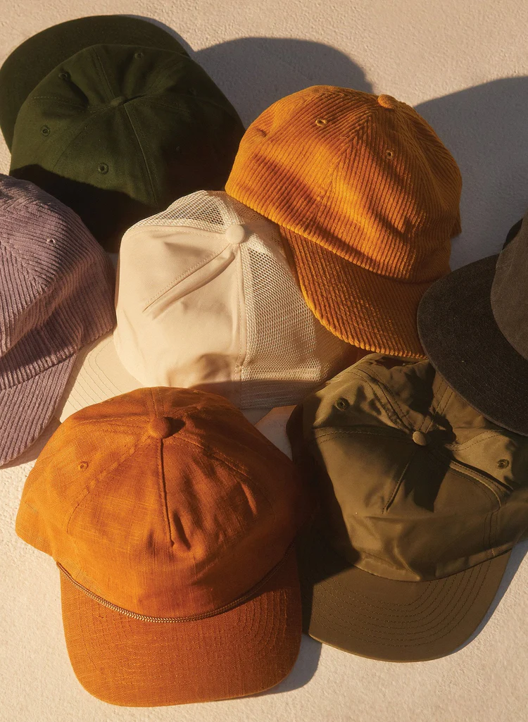 A branded cap, knit beanie and tote bag with small tonal logos laid out on a table