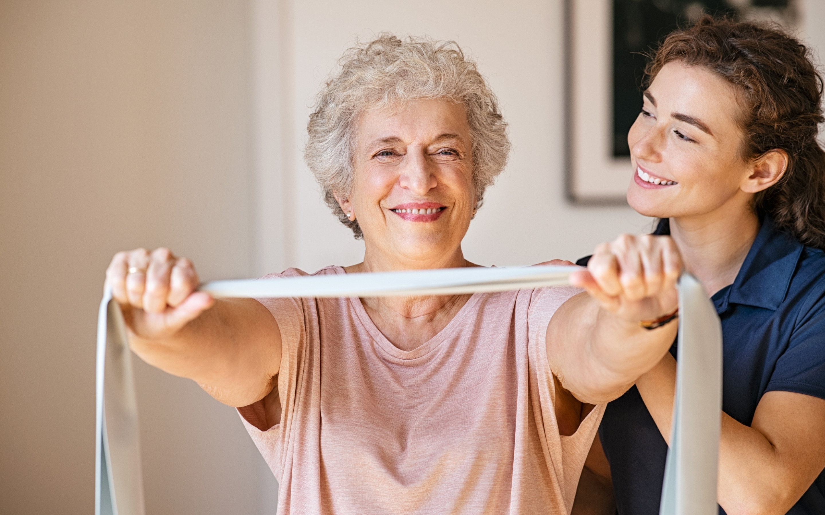 A physiotherapist guiding an older woman through a resistance band exercise during a home visit