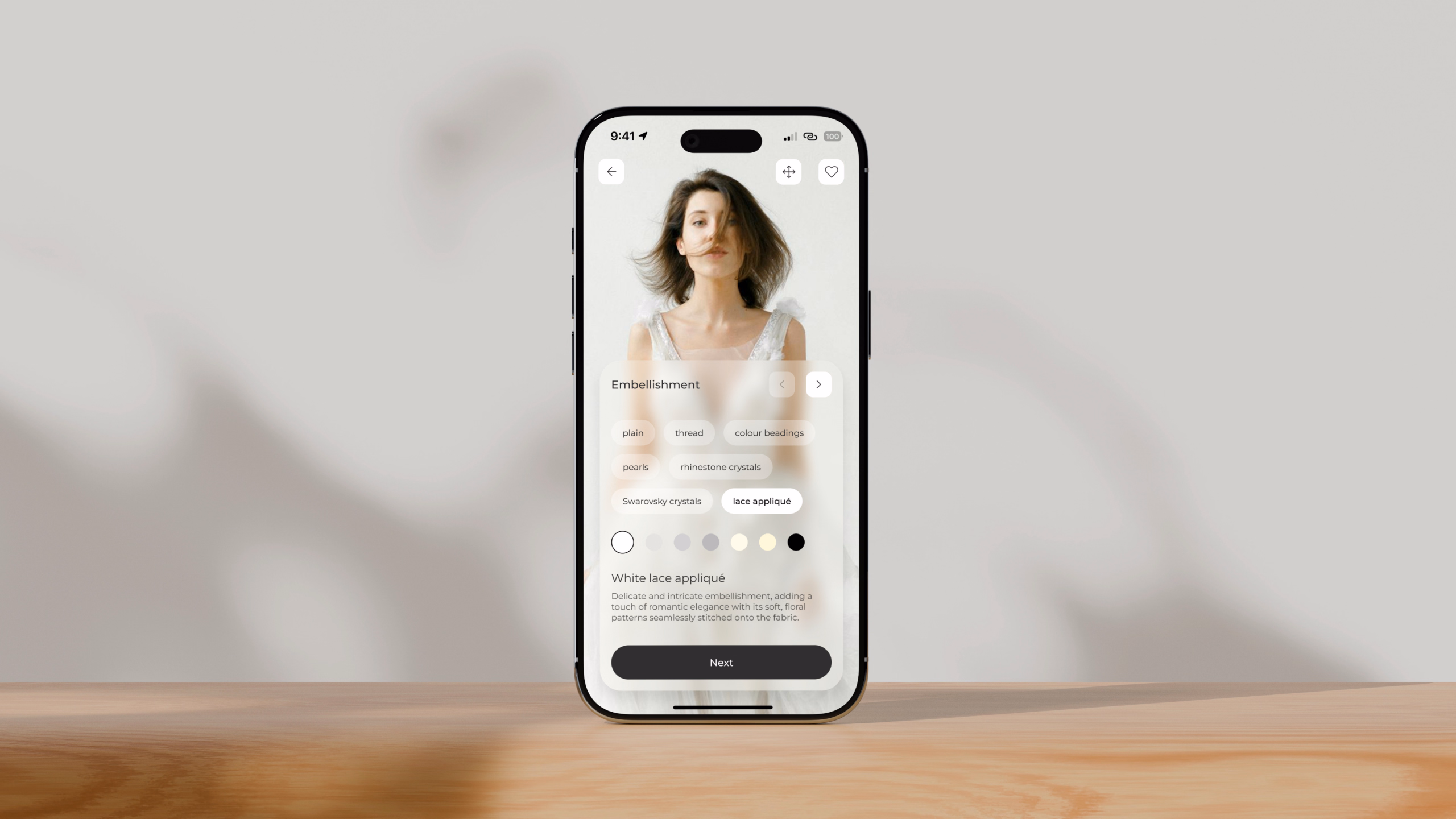 Anomalie wedding dress customization app displayed on a phone on a wooden surface