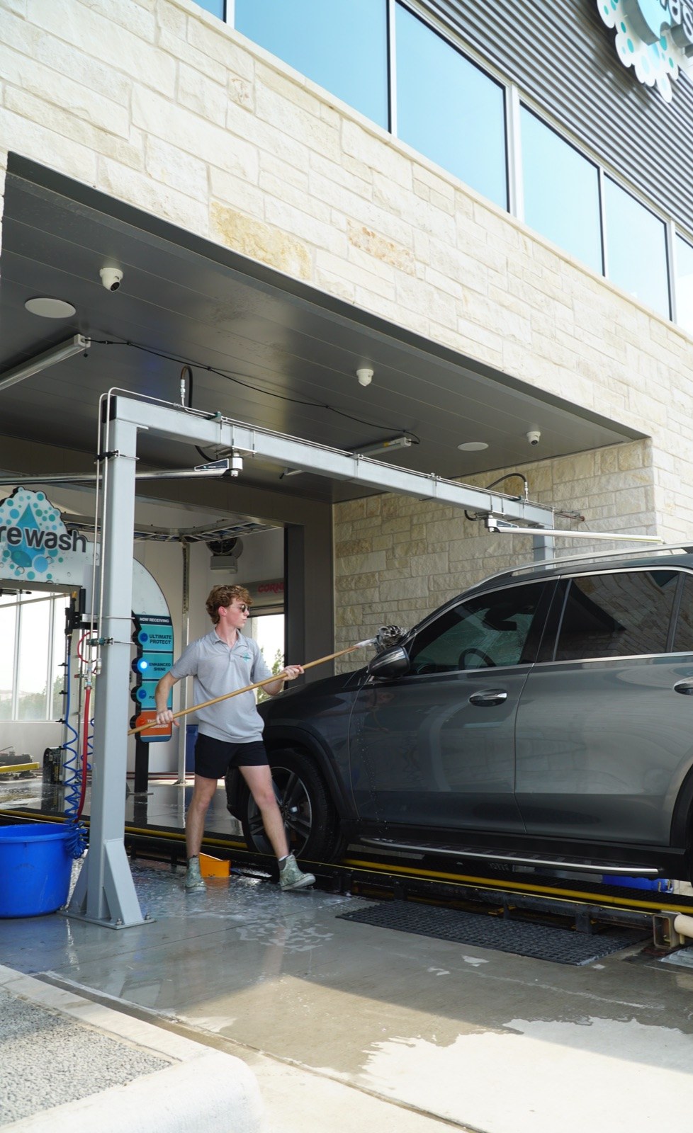 A Purewash attendant hand-prepping an SUV on the way into the tunnel