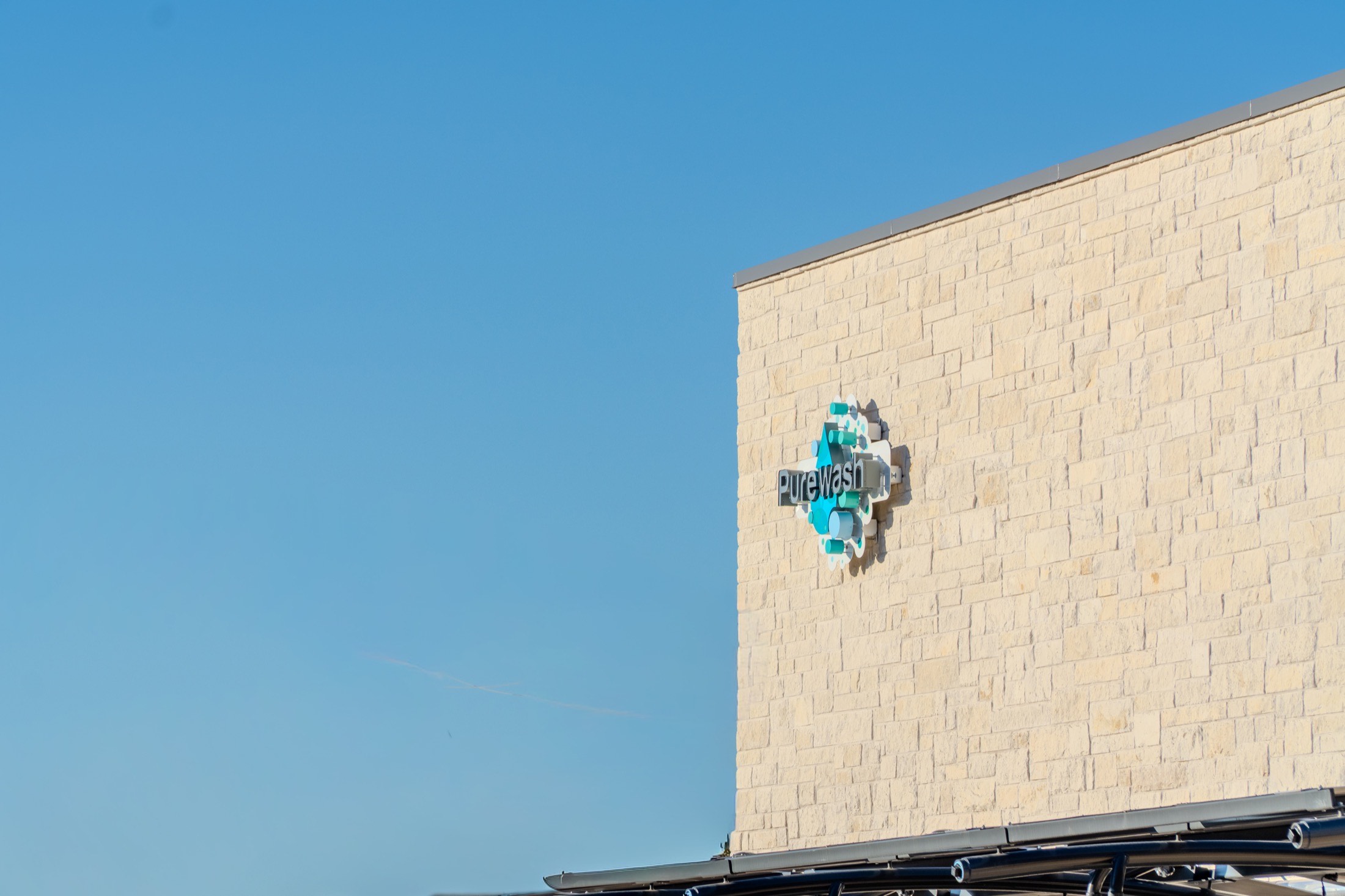 The Purewash sign on the limestone wall against open blue sky